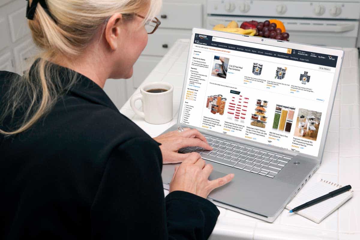 女人在厨房检查她的雷电竞官网网址笔记本电脑浏览在线购买食品容器,在哪里买食物容器