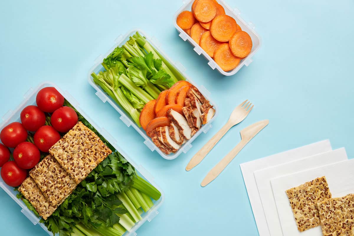 不同的蔬菜放在塑料容器里，旁边放着纸巾和其他塑料容器，塑料食物容器可以放在洗碗机里吗?＂width=