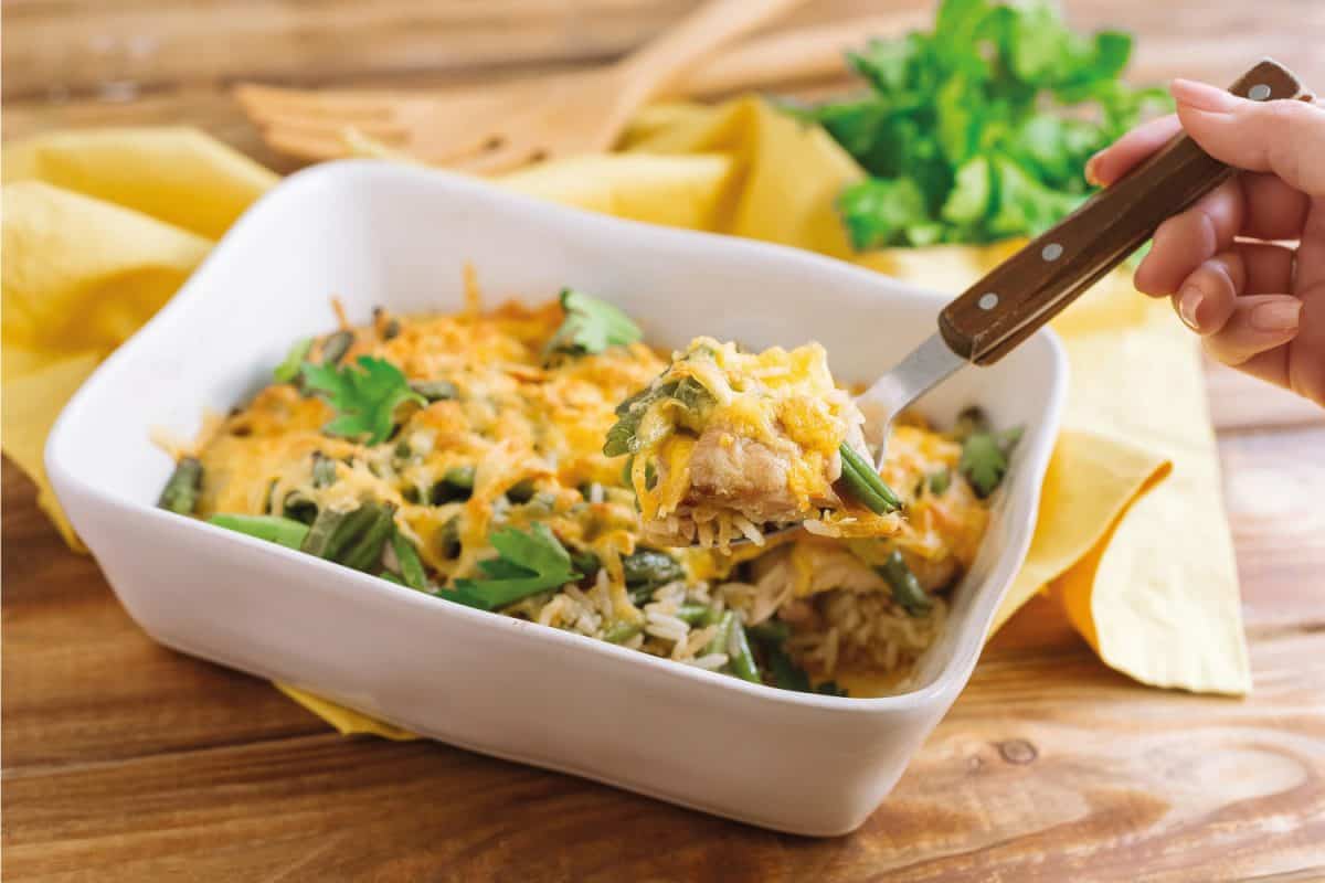 奶酪烤鸡柳饭,随着地壳和酱油。籼米和青豆。白色的木质茶几上的烤盘的腿