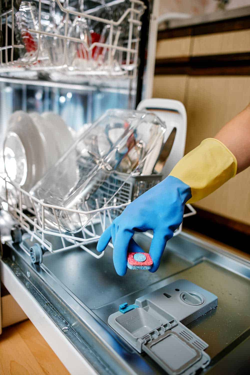 妇女将药片放入洗碗机洗涤剂盒