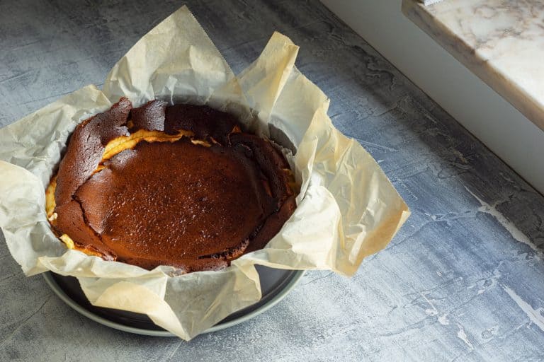 A newly baked cheesecake with parchment paper laid below, Which Way Does The Bottom Of A Springform Pan Go?