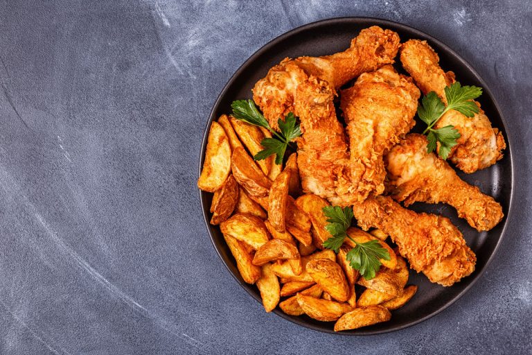 Golden brown deep fried chicken with fried potatoes on the side, What is the Best Pot to Fry Chicken? [3 Great Options!]