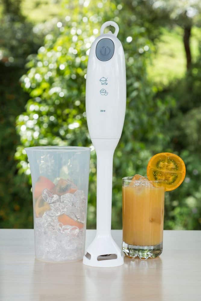 一杯冰和一只手搅拌机放在桌上