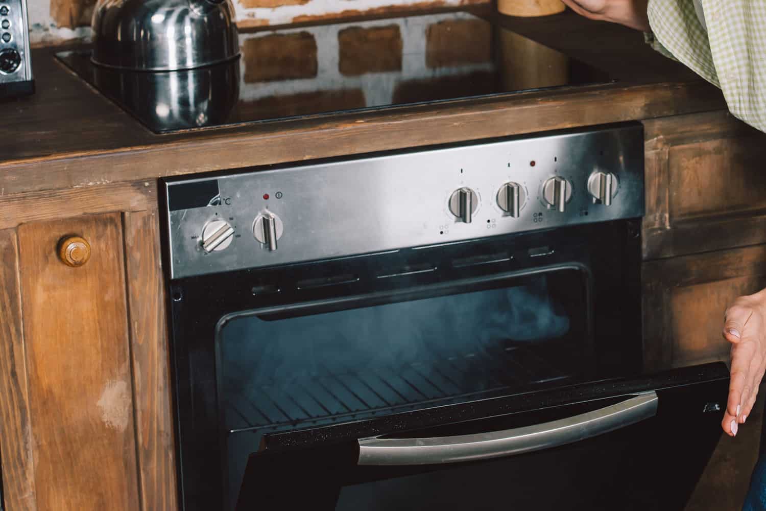 一个女人打开她冒烟的烤箱