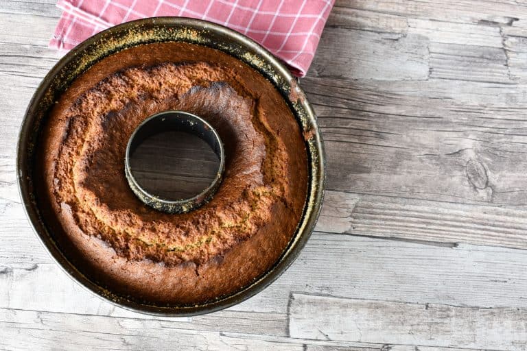 A freshly baked bundt cake placed on a wooden table, How Long Do You Bake A Cake In A Bundt Pan? [Plus Some Popular Recipes!]