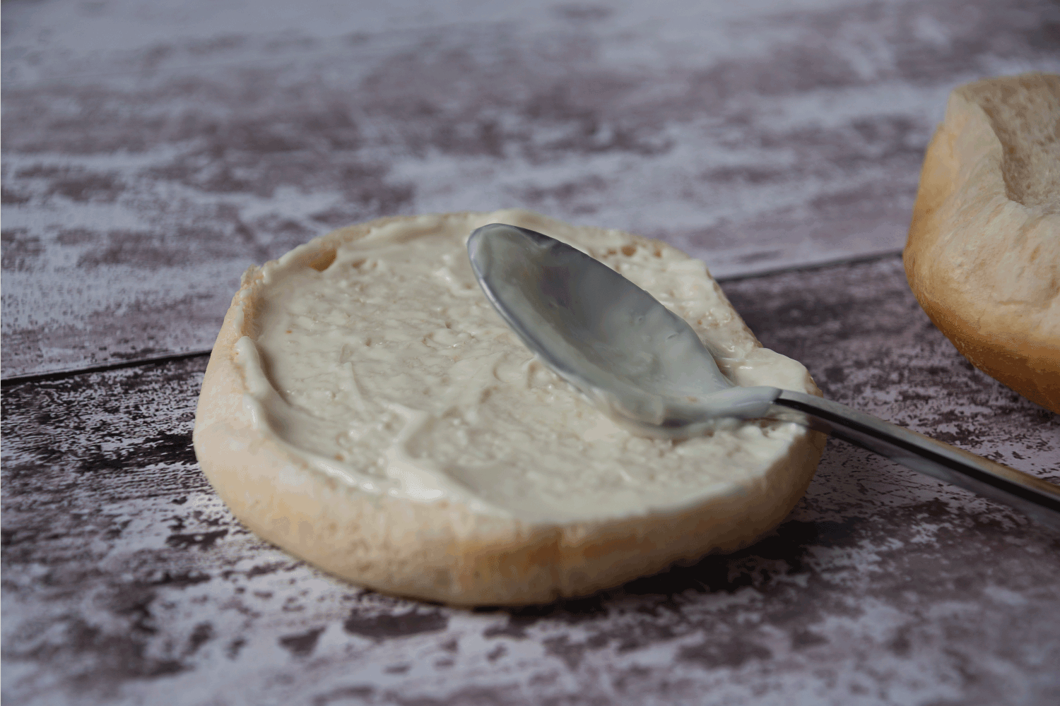 从侧面用茶匙的角度看，一个白色的汉堡圆面包底座上覆盖了蛋黄酱