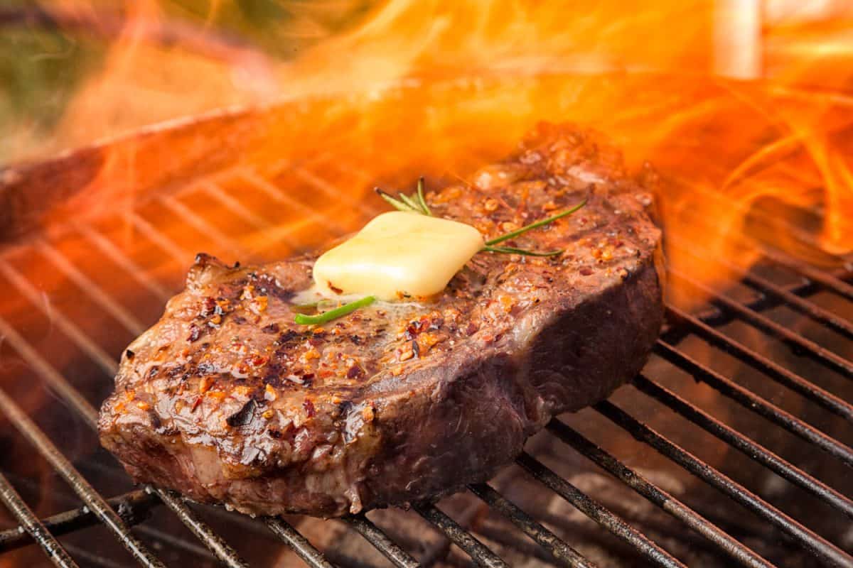 与黄油和火焰烤肋眼牛排被煮熟。