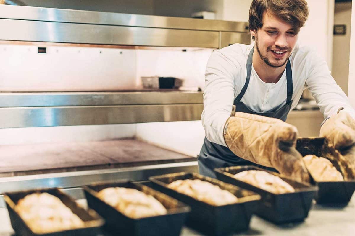 年轻的贝克拿出新鲜烤面包的热锅