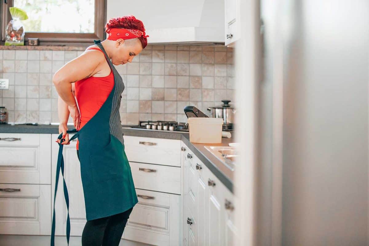 成年妇女在家庭厨房穿围裙雷电竞官网网址