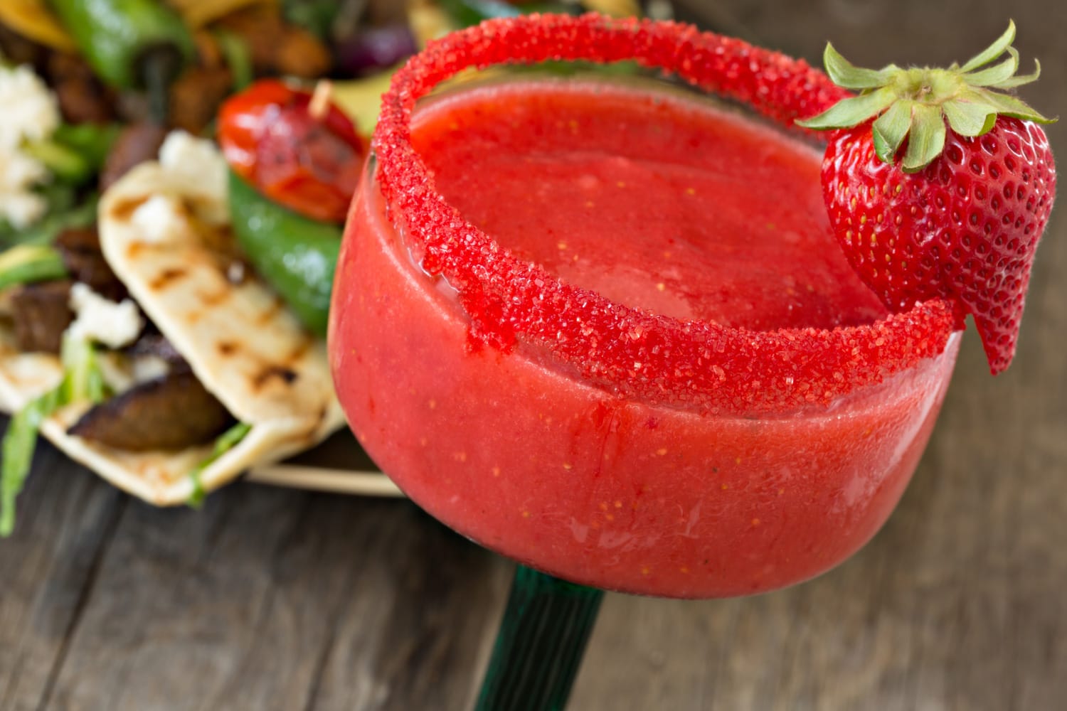 一个极端的特写镜头一杯草莓玛格丽塔和牛肉塔可在后台。