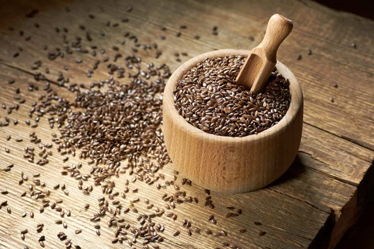 亚麻籽在乡村木制碗散落在木材和粮食