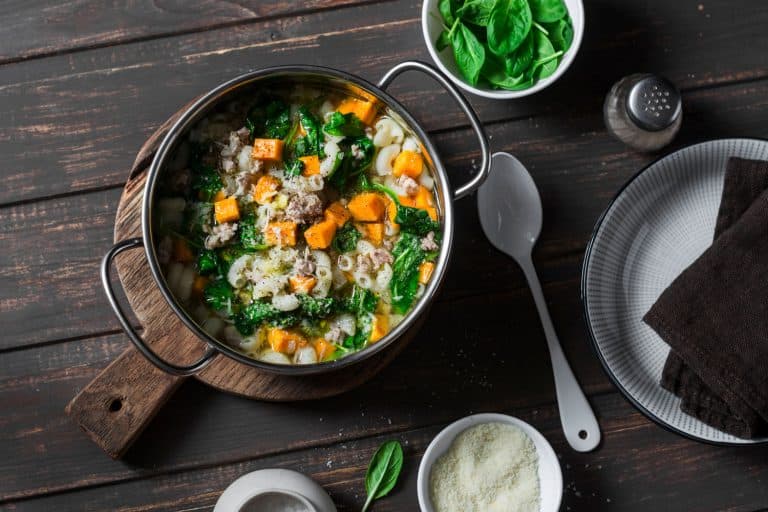 红薯与菠菜和面条和猪肉香肠汤一锅在黑暗的背景下,前视图,使最好的锅汤是什么?