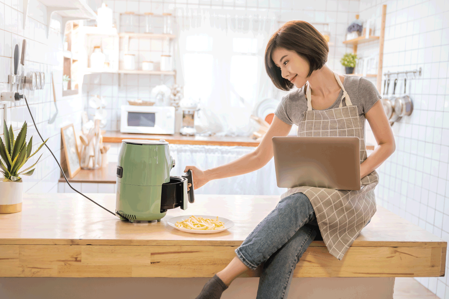 亚洲女孩在厨房烹饪土豆炸的空气炸锅机回家雷电竞官网网址