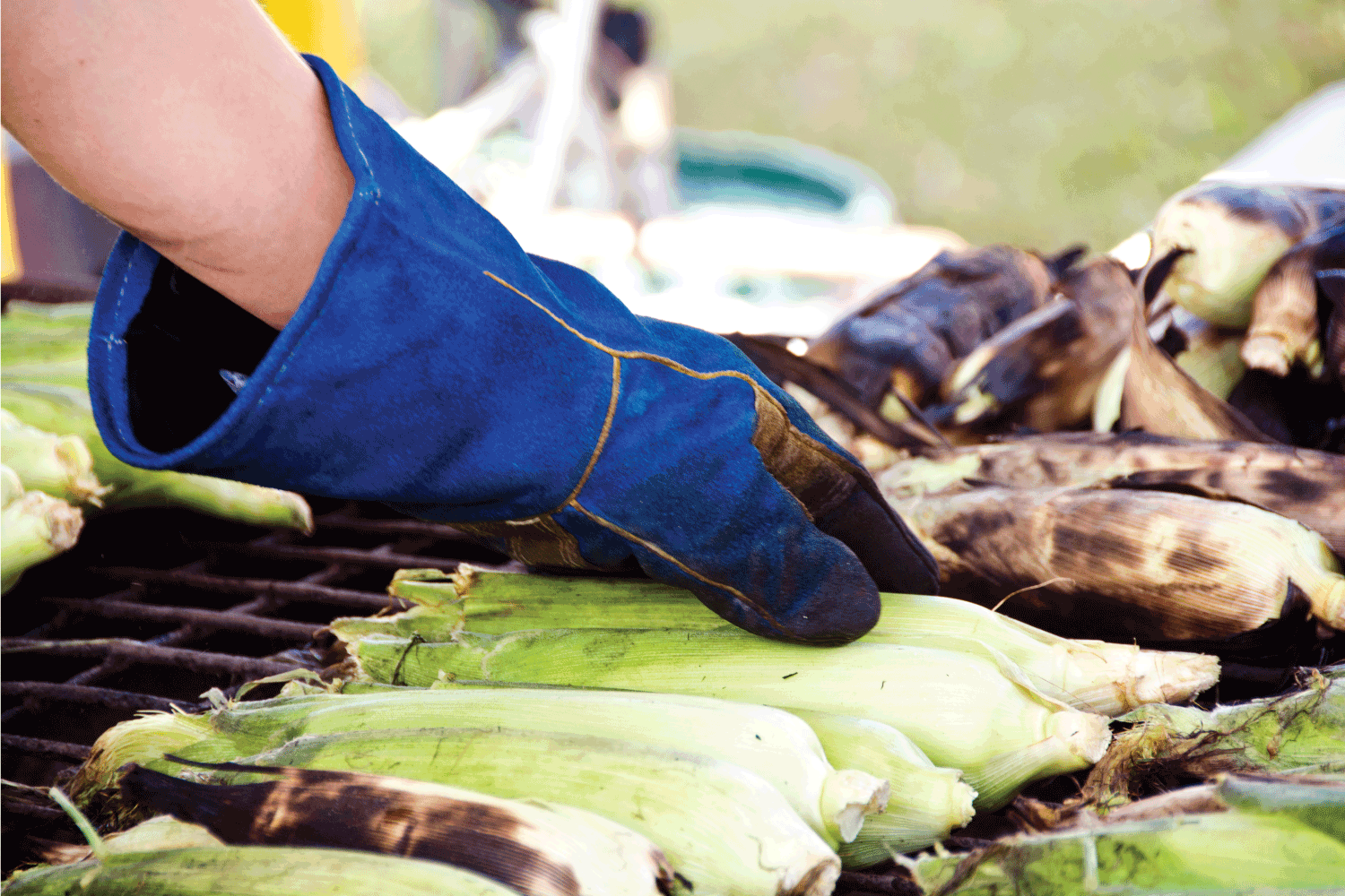 厨师把玉米穗在烤架上烤玉米。