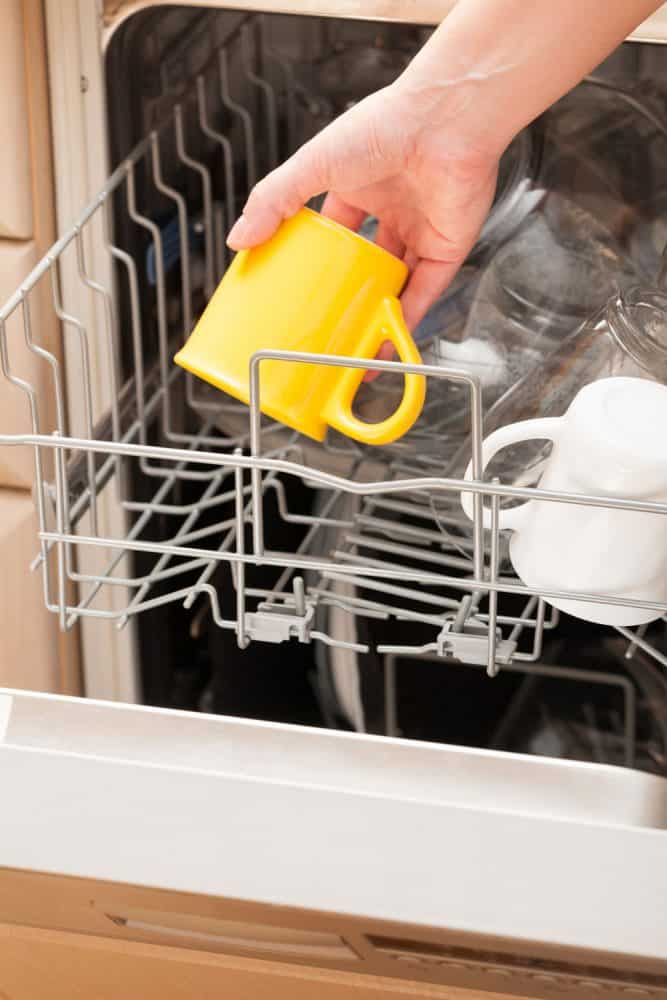 一个女人洗黄颜色的Le Creuset杯子