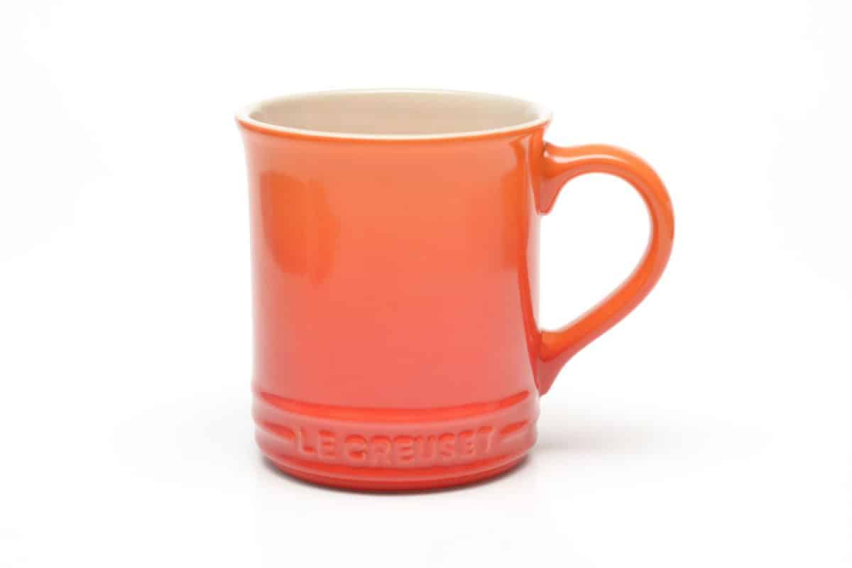 黄色和红色渐变颜色的Le Creuset杯白色背景