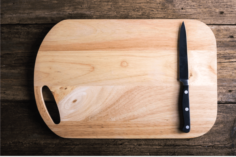 Empty-chopping-board-with-a-sharp-paring-knife-on-a-distressed-grunge-wooden-table-in-a-rustic-雷电竞官网网址kitchen