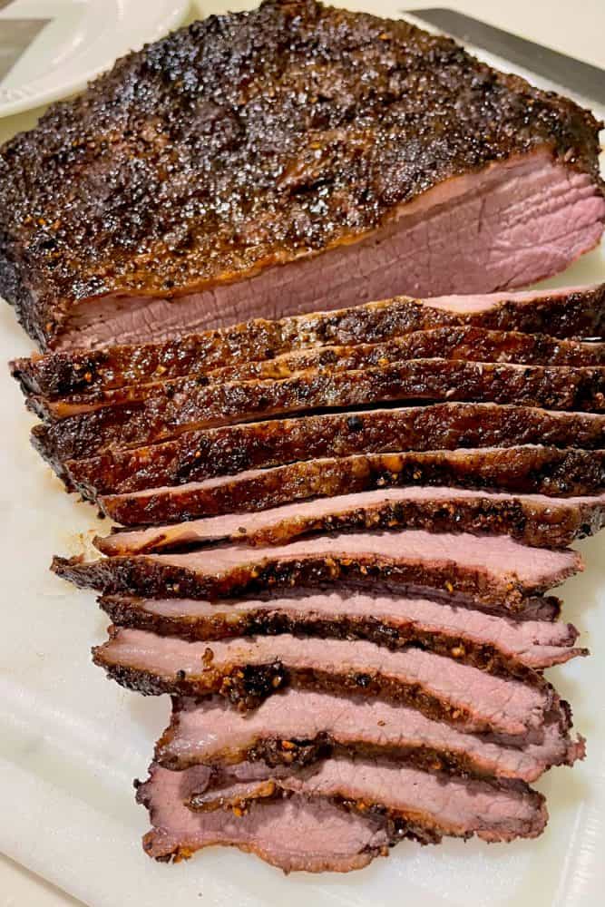 Evenly cut medium rare beef brisket on a chopping board