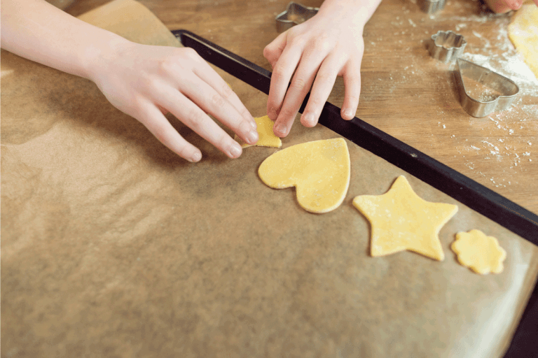 Kids making shaped cookies placing them in cookie sheet for baking. Jelly Roll Pan Vs Cookie Sheet Vs Baking Sheet - What Are The Differences
