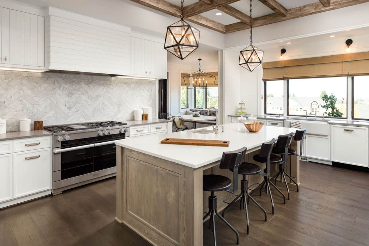 豪华和乡村设计的厨房内部有木地板，白色橱柜，和一个带吊灯的厨雷电竞官网网址房岛