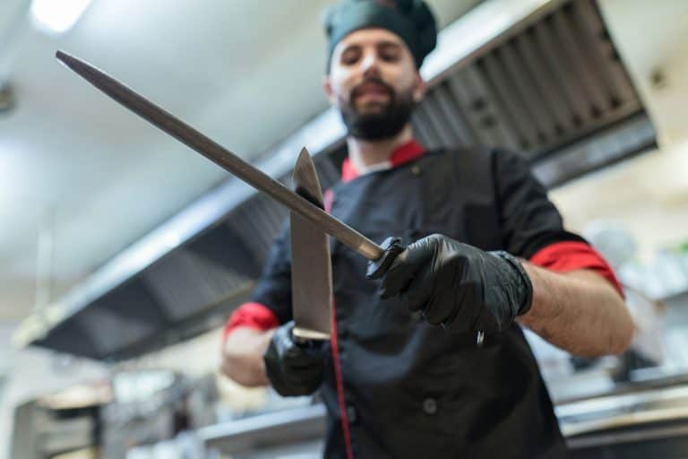 年轻男性厨师在餐厅厨房磨他的刀,你能把那些娇生惯养的厨师刀洗碗机吗?雷电竞官网网址