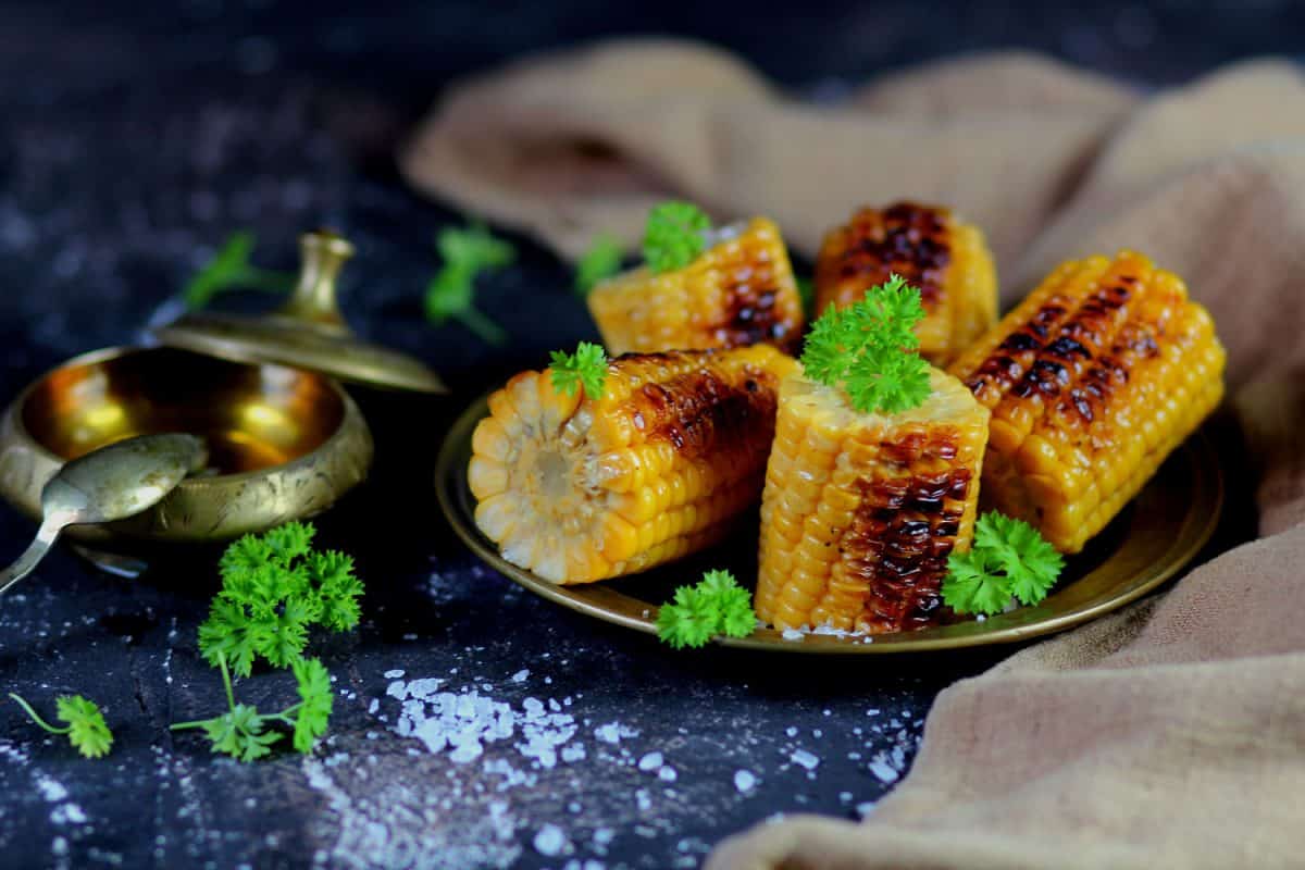 美味的烤玉米棒放在一个小不锈钢盘上