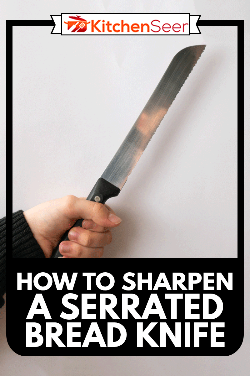 白人的手放在黑色毛衣拿着面包刀,孤立在白色的背景下,如何提高一个锯齿状的面包刀