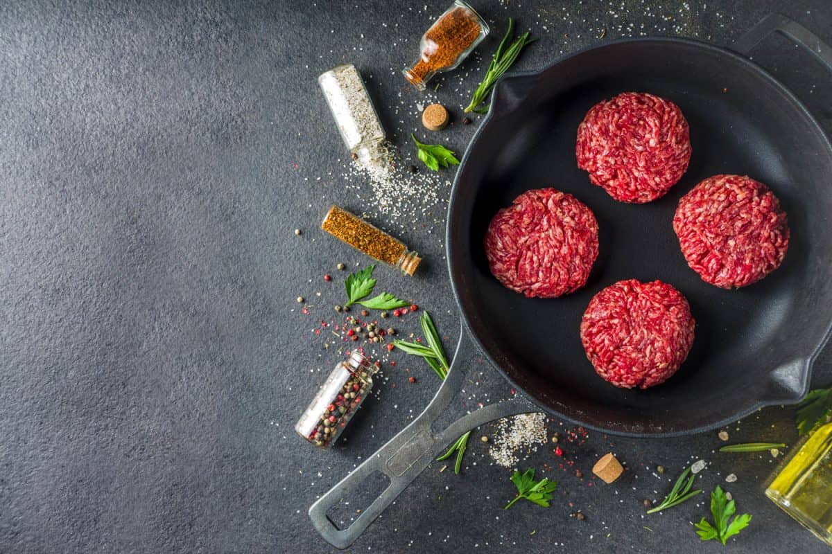 生肉馅牛肉汉堡肉饼。烹调肉类和汉堡背景与橄榄oi,多久你两边煎或烧烤汉堡吗?