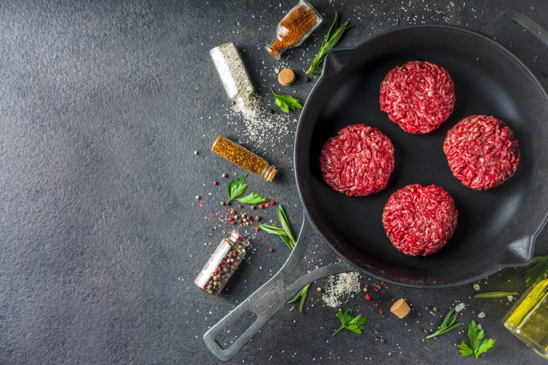 生肉馅牛肉汉堡肉饼。烹调肉类和汉堡背景与橄榄oi,多久你两边煎或烧烤汉堡吗?