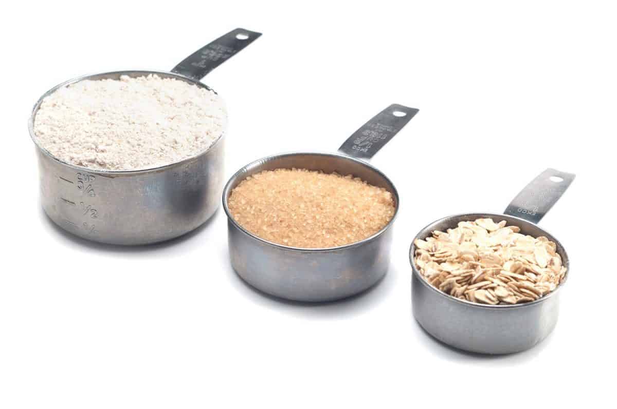 三个逐渐变大的量杯，盛满面粉和糖，生的和燕麦
