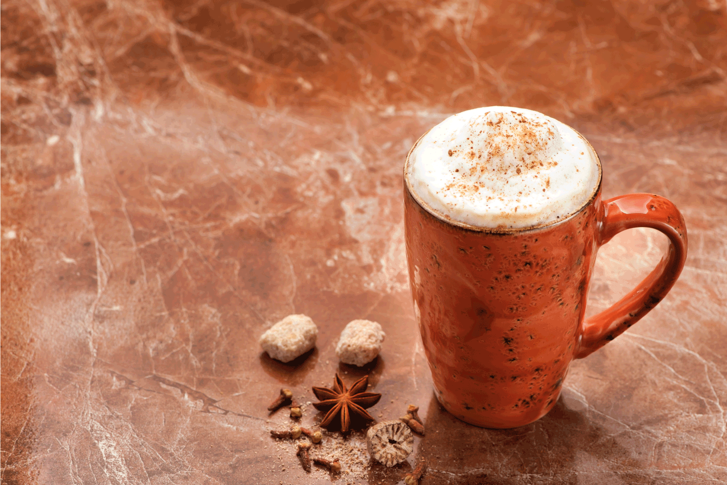 卡布奇诺咖啡和香料。黑色大理石背景