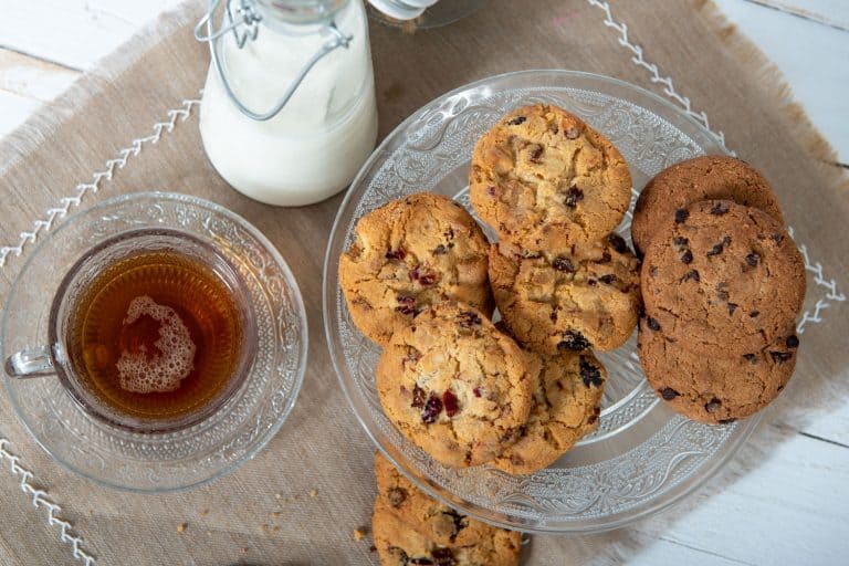 A glass bowl filled with chocolate chips and a jar of milk, How Long Do Chocolate Chip Cookies Last?