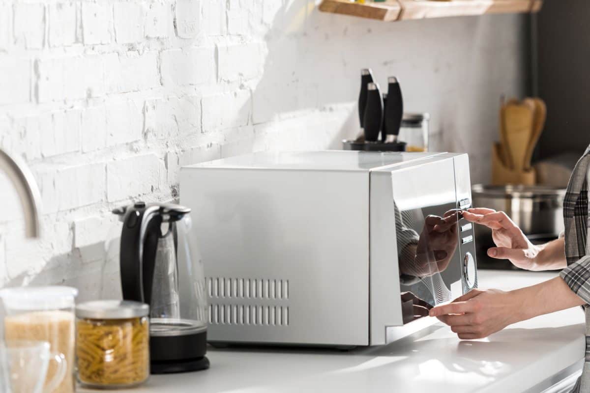 一个女人早上把一杯牛奶放进微波炉