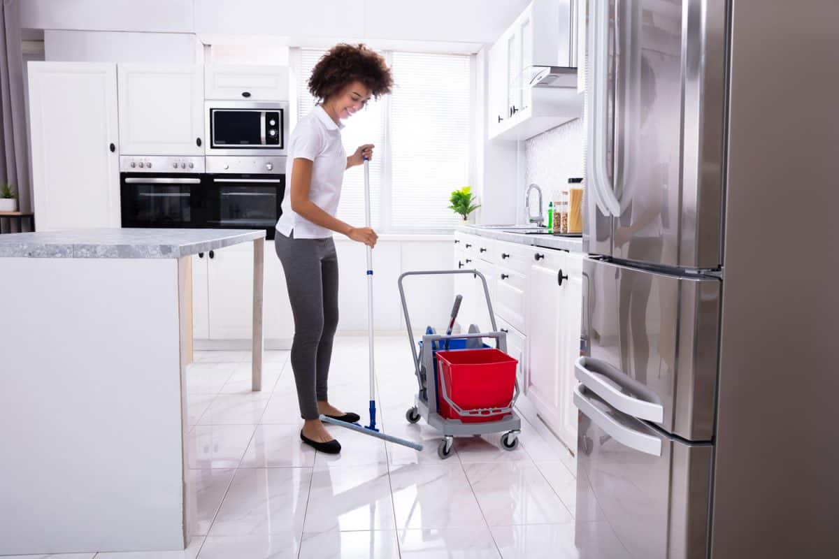 现代厨房里，女清洁工用拖把清洁白色地板雷电竞官网网址
