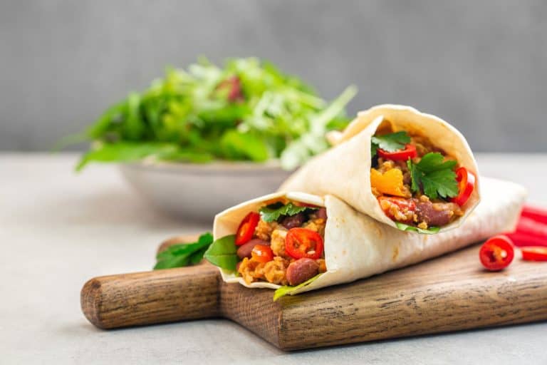 玉米粉薄烙饼上加上炸碎肉、煮熟的豆类、番茄、辣椒酱和辣椒。沙拉在后台,在玉米饼暖热玉米饼(干燥的情况下)