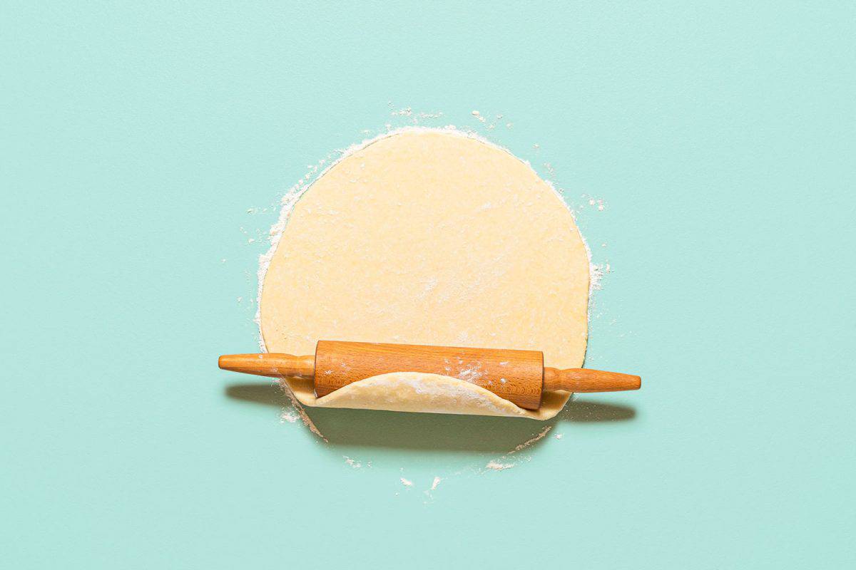 滚动一个糕点面团浅蓝色背景