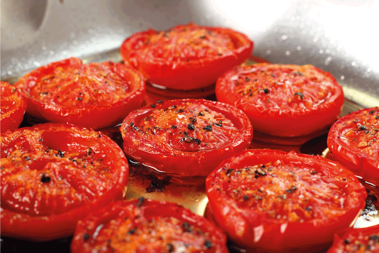 Slow Roasted Tomatoes in a stainless steel pan with olive oil