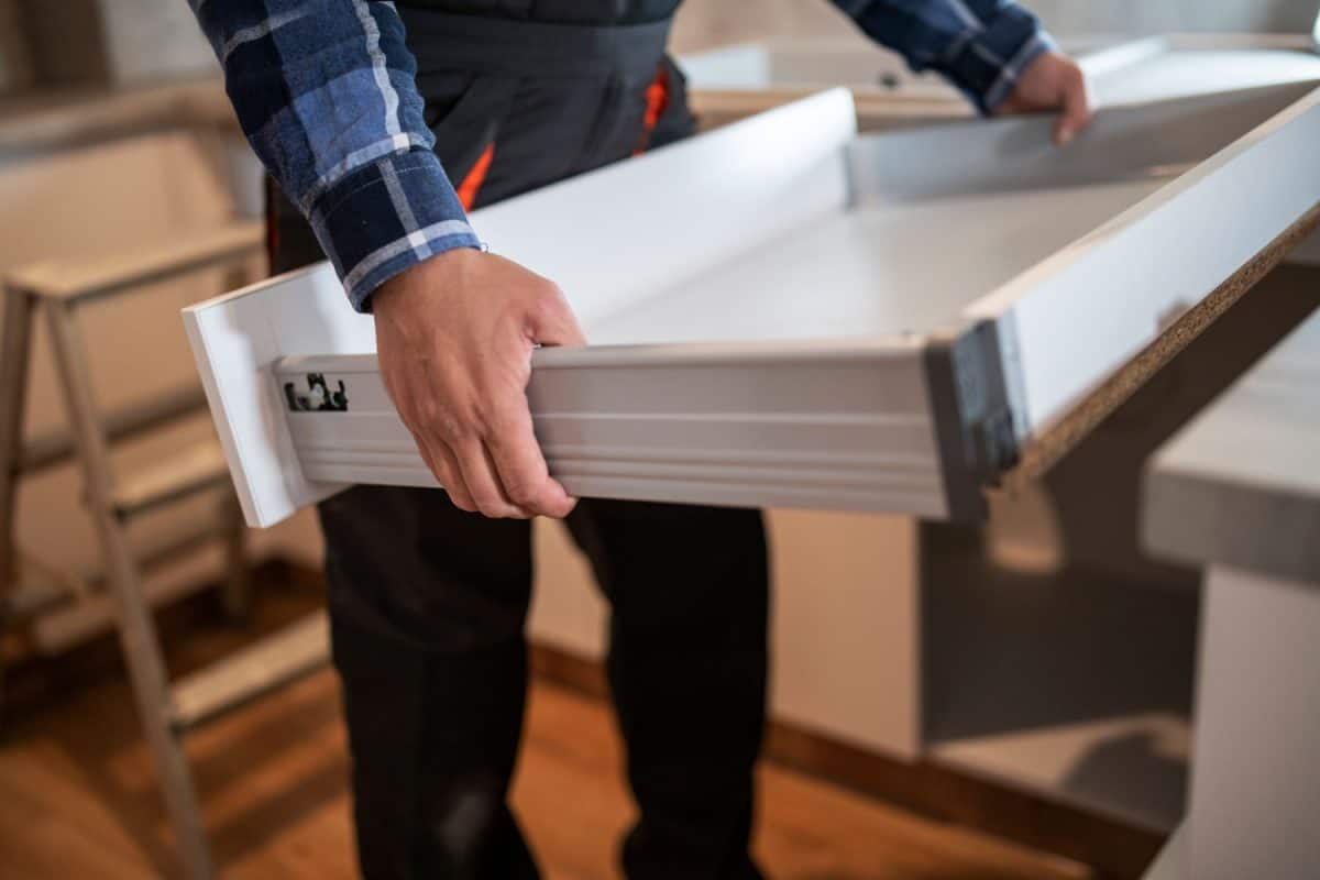 在新厨房里，一个不知名的工人拿着抽屉和调整抽屉雷电竞官网网址