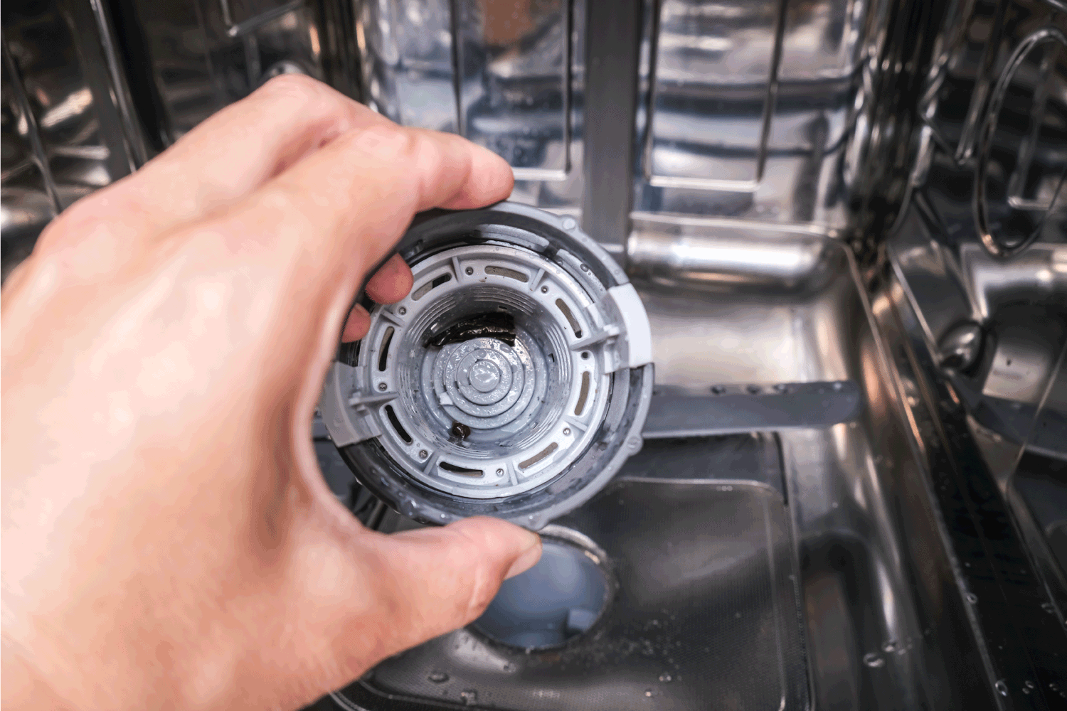一只手拿出洗碗机滤网清洗它，dis洗衣机清洗概念，厨房家电的保养和保养雷电竞官网网址