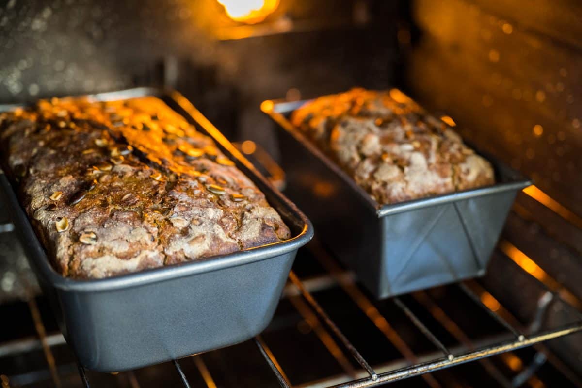 密切的大型和小型锅乡村面包面包坐在炉架,由室内光线照亮,准备搬家。