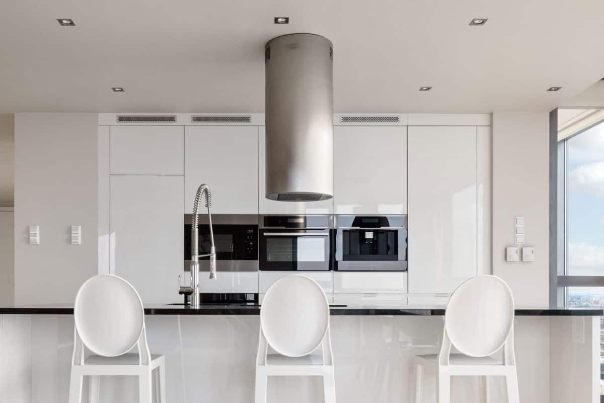 华丽的白色设计厨房，厨房和早餐吧台上有黑色台面雷电竞官网网址