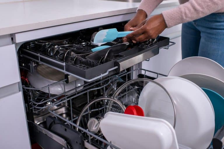 Woman unloading dishwasher after washing, How To Secure A Dishwasher To The Cabinet