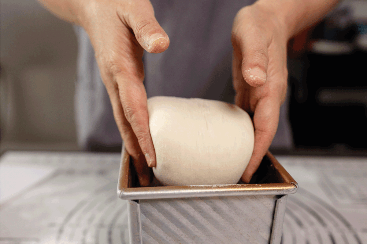 baker putting bread dough into loaf pan