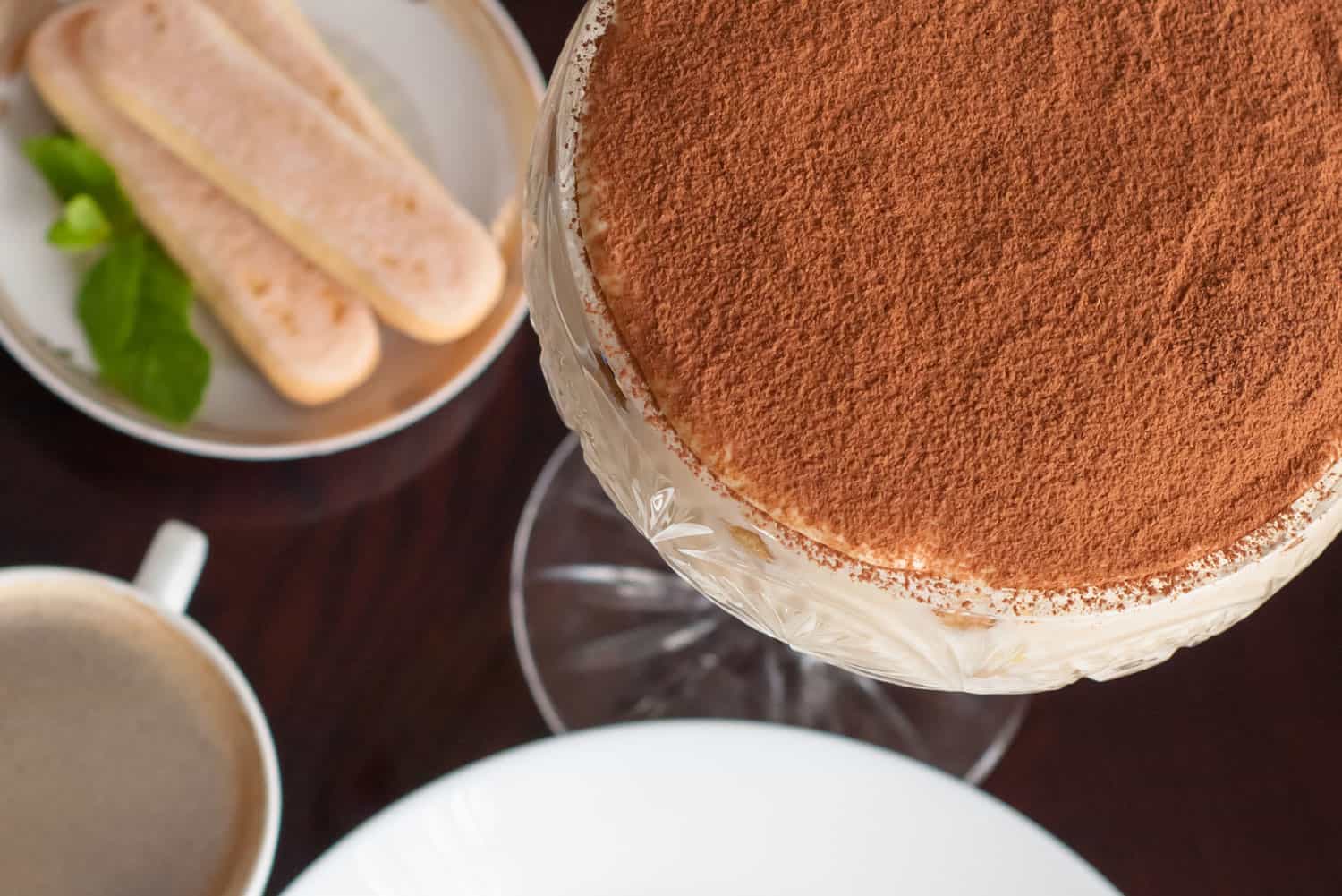 Luxurious Tiramisu cake in a glass on a dark background decorated with mint