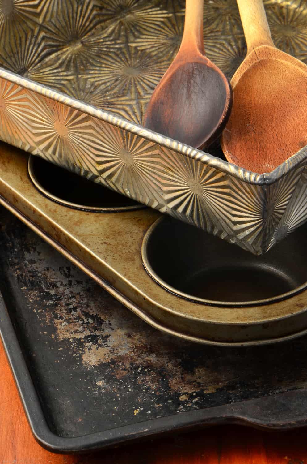 A collection of old, well used metal bakeware in vertical format