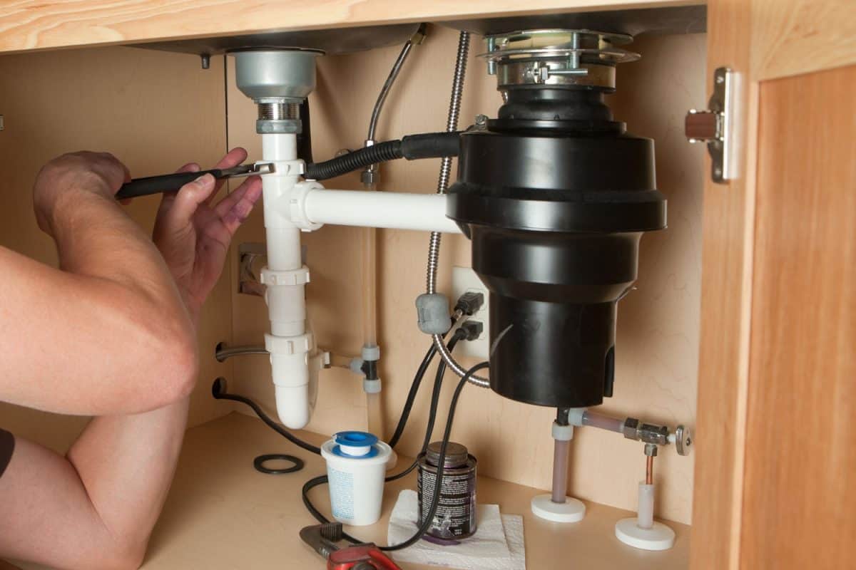 一个工人检查垃圾处理机器水池下面