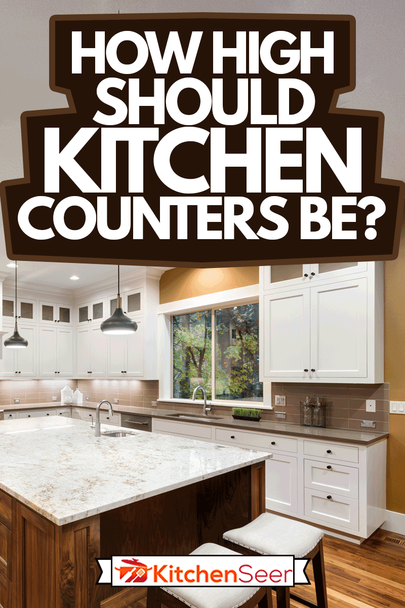 大厨房室内岛雷电竞官网网址,水槽,白色的橱柜,吊坠的灯光,和硬木地板在新豪宅,厨房柜台应该多高?