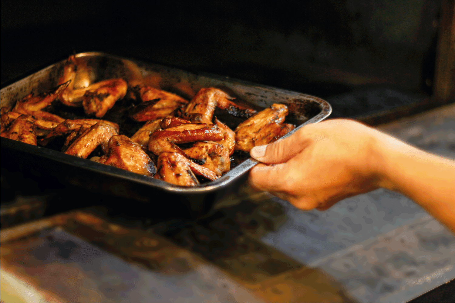 年轻人把鸡翅放进烤箱