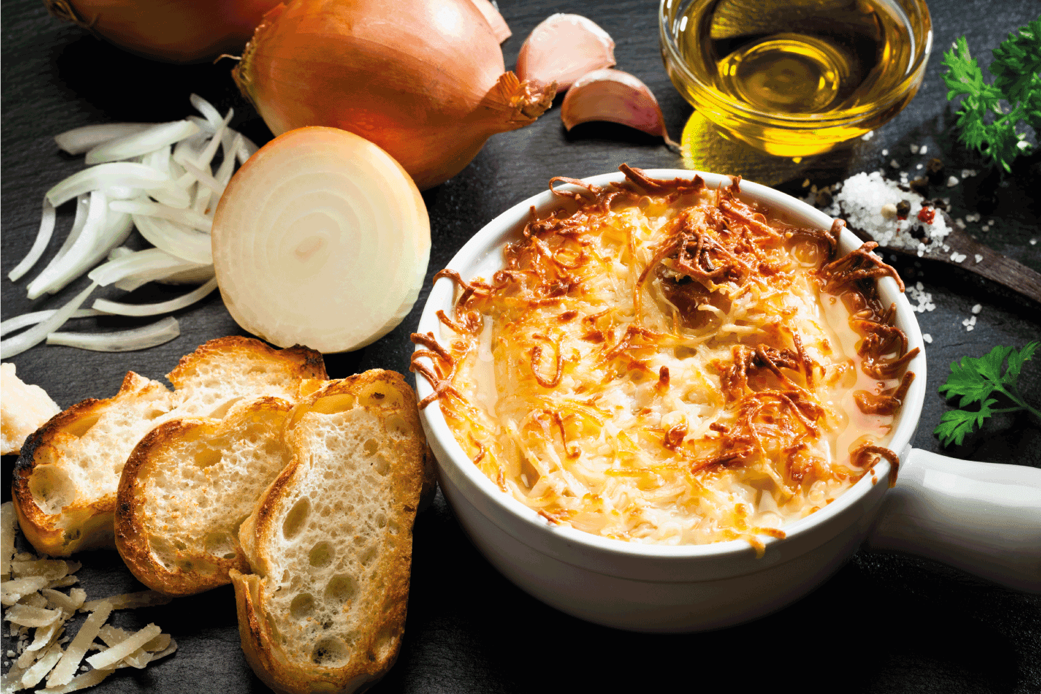 黑色的桌子和一个洋葱汤碗烹饪所有的成分。