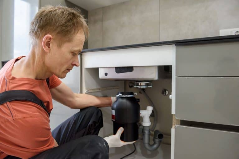 The worker is installing a household waste shredder for the kitchen sink, 1/2 Hp Vs 3/4 Hp Garbage Disposal: Which To Choose